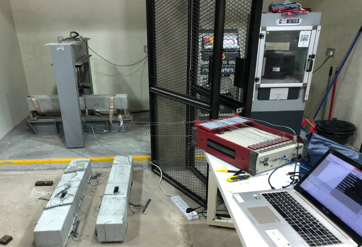 Beams under flexure and displacement testing, with sensors wired to a datalogger